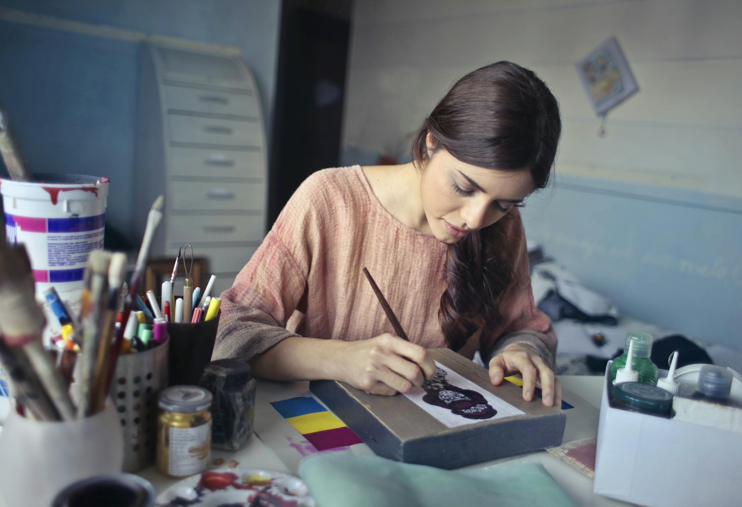 Female artist deeply engaged in painting at her creative studio workspace.